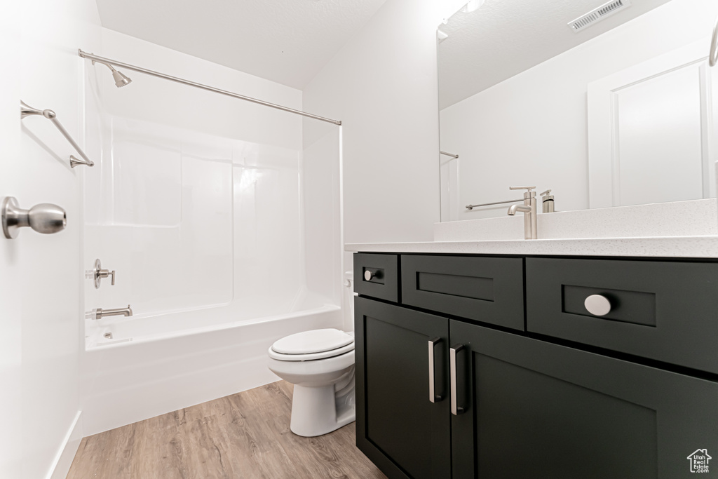 Bathroom with wood finished floors, vanity, and shower / bath combination
