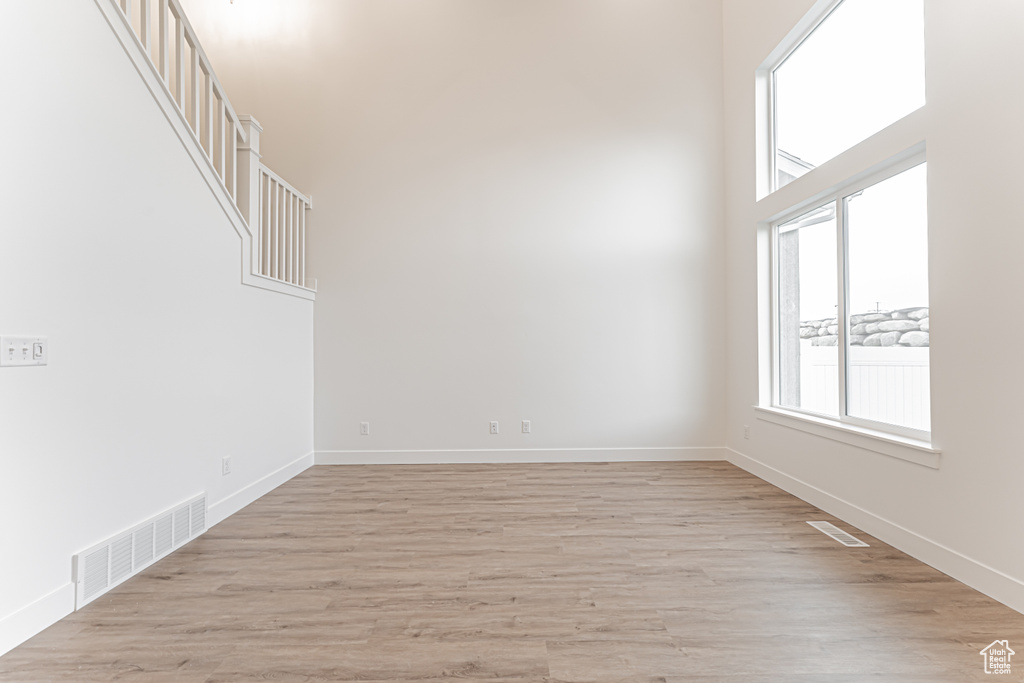 Spare room with light wood-style floors and a towering ceiling