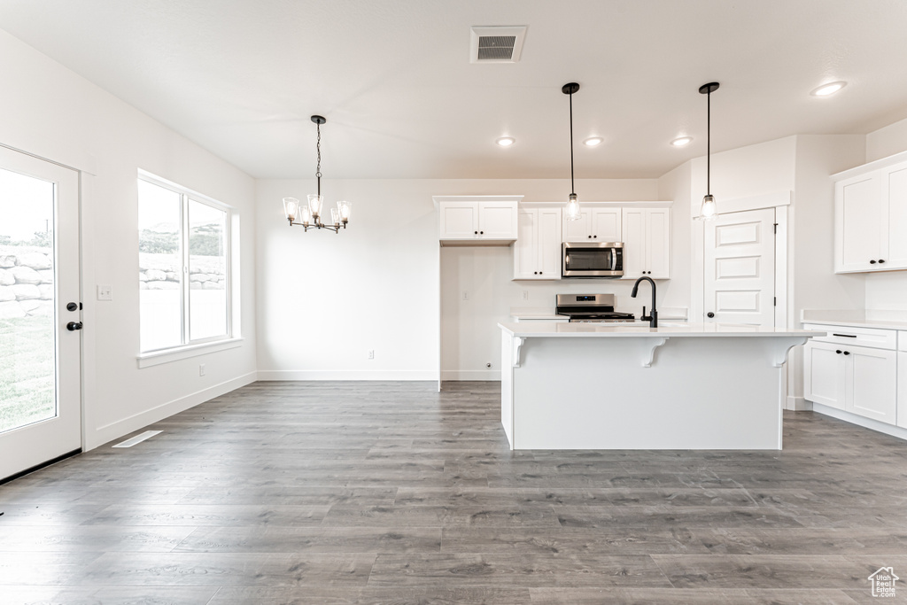 Kitchen featuring stainless steel appliances, light countertops, white cabinetry, a chandelier, and recessed lighting