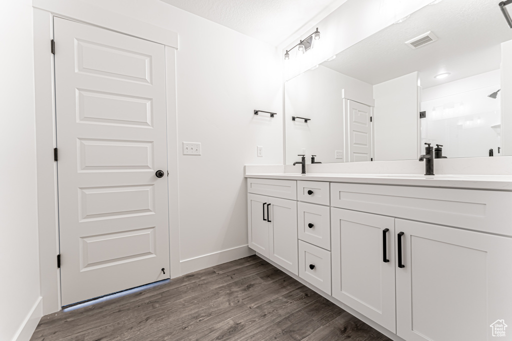 Full bath with double vanity, wood finished floors, and an enclosed shower