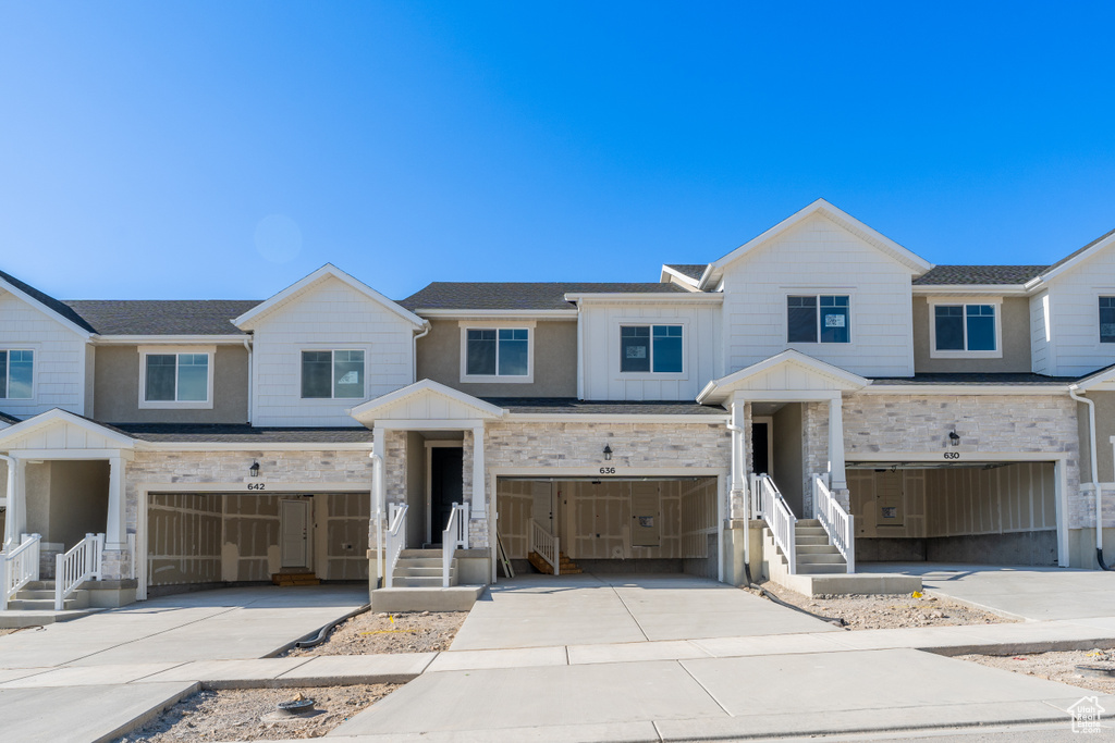View of front of house with a garage, driveway, stone siding, and board and batten siding