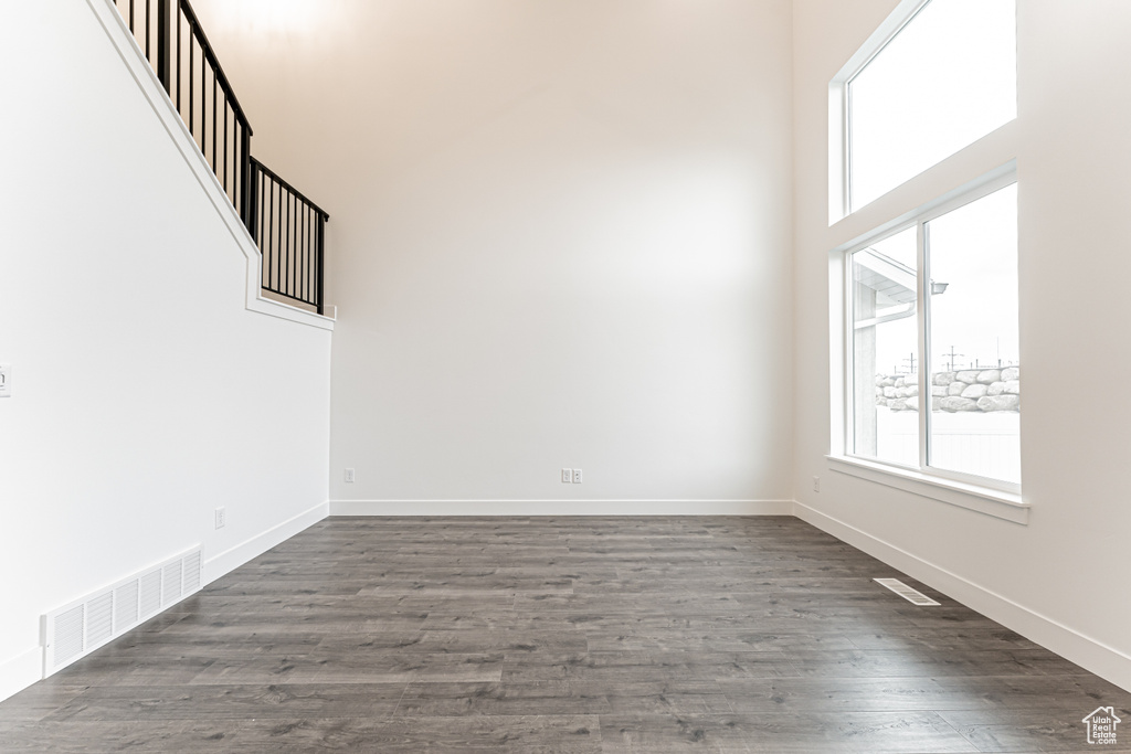 Spare room featuring healthy amount of natural light, dark wood finished floors, and a towering ceiling