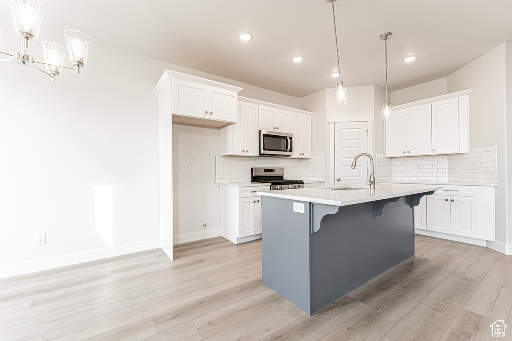 Kitchen featuring appliances with stainless steel finishes, light wood finished floors, tasteful backsplash, and recessed lighting