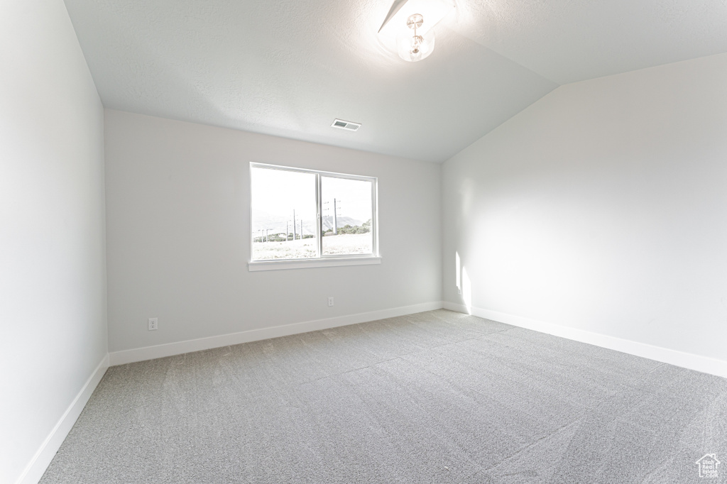Spare room with vaulted ceiling and light colored carpet