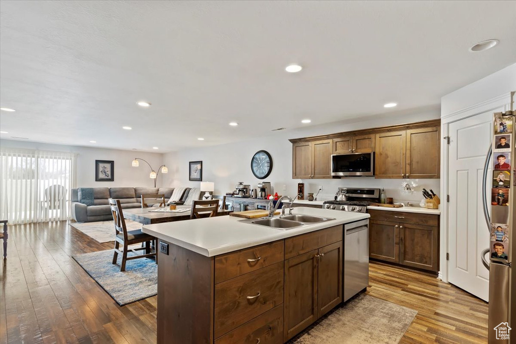 Kitchen with wood finished floors, recessed lighting, a sink, light countertops, and appliances with stainless steel finishes