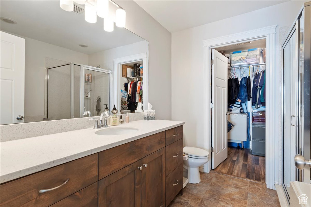 Bathroom with a spacious closet, toilet, a stall shower, and vanity
