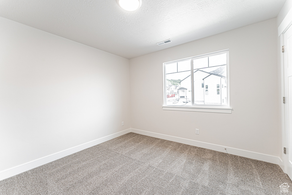 Carpeted empty room with baseboards and a textured ceiling