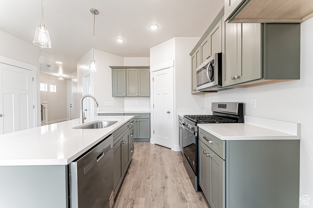 Kitchen with appliances with stainless steel finishes, gray cabinetry, light wood finished floors, and recessed lighting