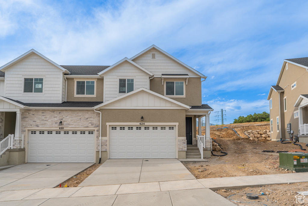 View of front of house featuring stone siding, concrete driveway, an attached garage, and board and batten siding