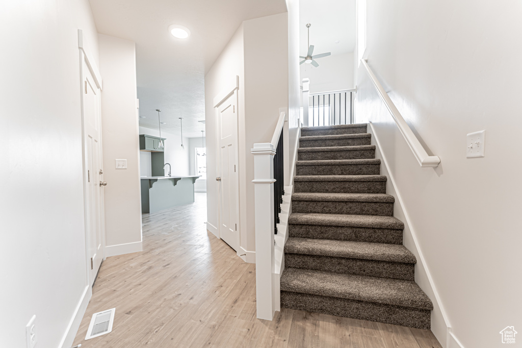 Staircase with a ceiling fan and wood finished floors
