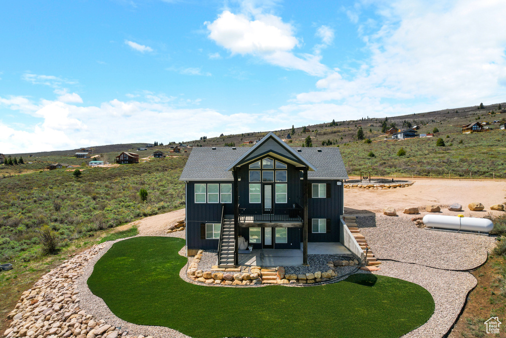 View of front of house with stairway, board and batten siding, a patio, and a front yard
