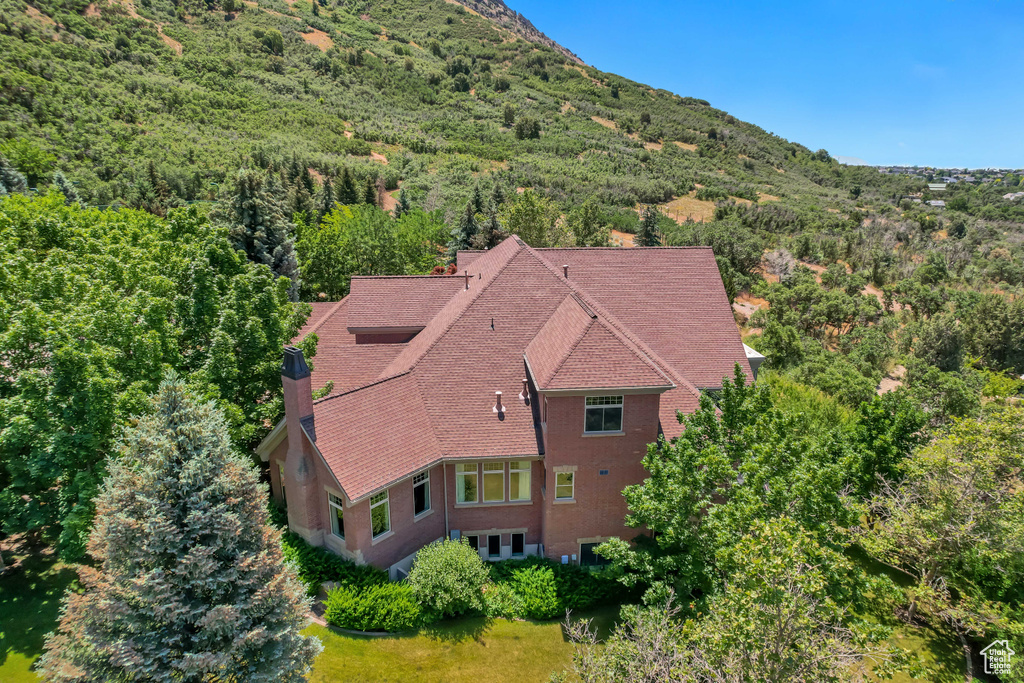 Aerial view of property and surrounding area featuring a heavily wooded area and mountains