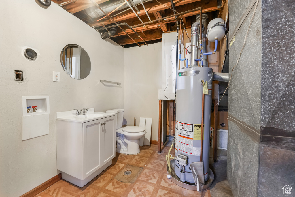 Bathroom with gas water heater, toilet, vanity, and baseboards