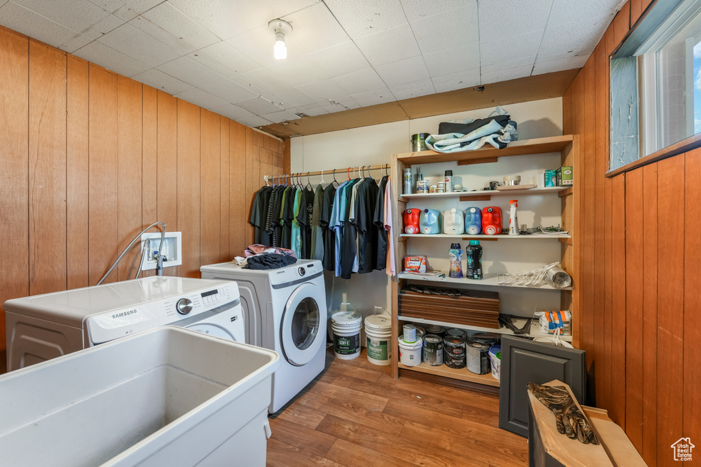Laundry area featuring wood walls, laundry area, wood finished floors, independent washer and dryer, and a sink