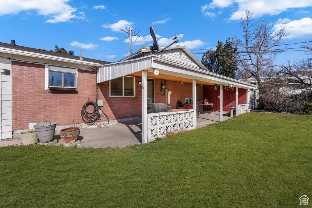 Rear view of house featuring a yard, brick siding, and a patio area