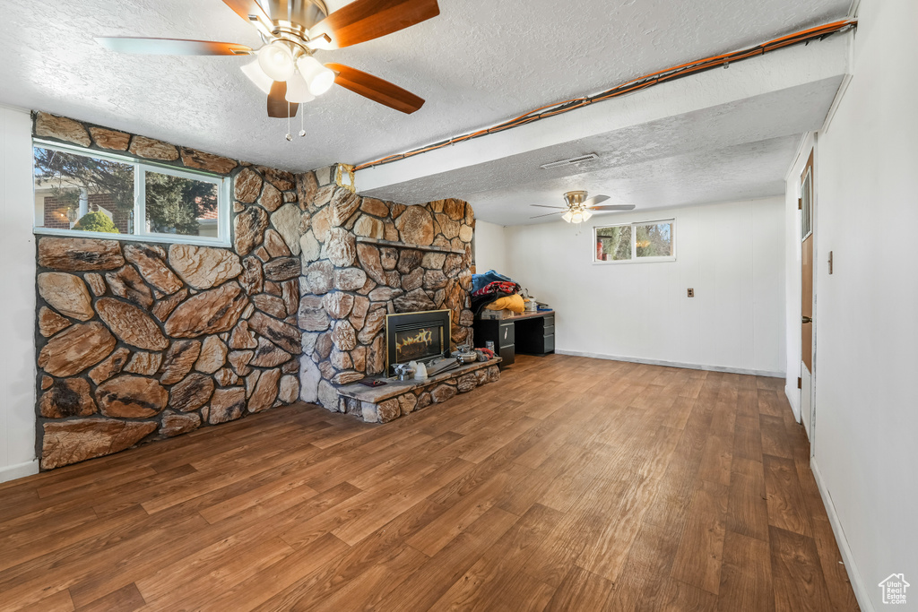 Unfurnished living room with a healthy amount of sunlight, a textured ceiling, and wood finished floors