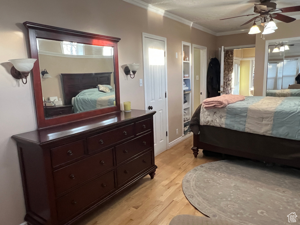 Bedroom with light wood finished floors, crown molding, and a ceiling fan