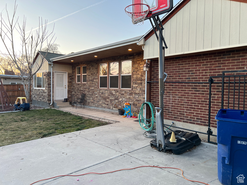 Exterior space featuring stone siding, entry steps, a yard, and fence