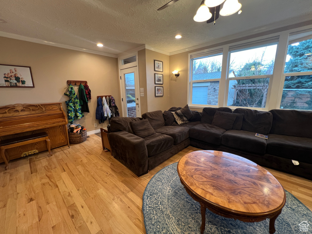 Living room with ornamental molding, a textured ceiling, recessed lighting, light wood finished floors, and ceiling fan