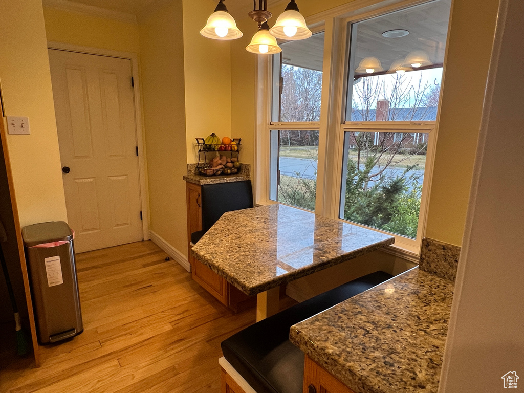 Dining space featuring crown molding, baseboards, light wood-type flooring, and a chandelier