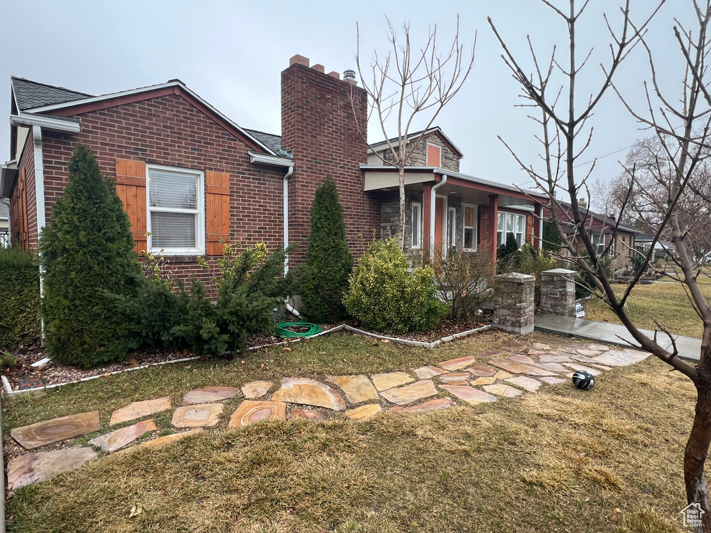 View of front of home with brick siding and a chimney