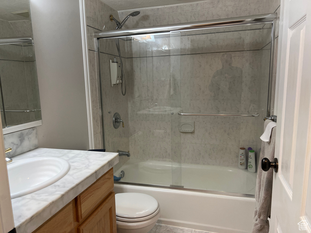 Full bath featuring vanity, toilet, and bath / shower combo with glass door