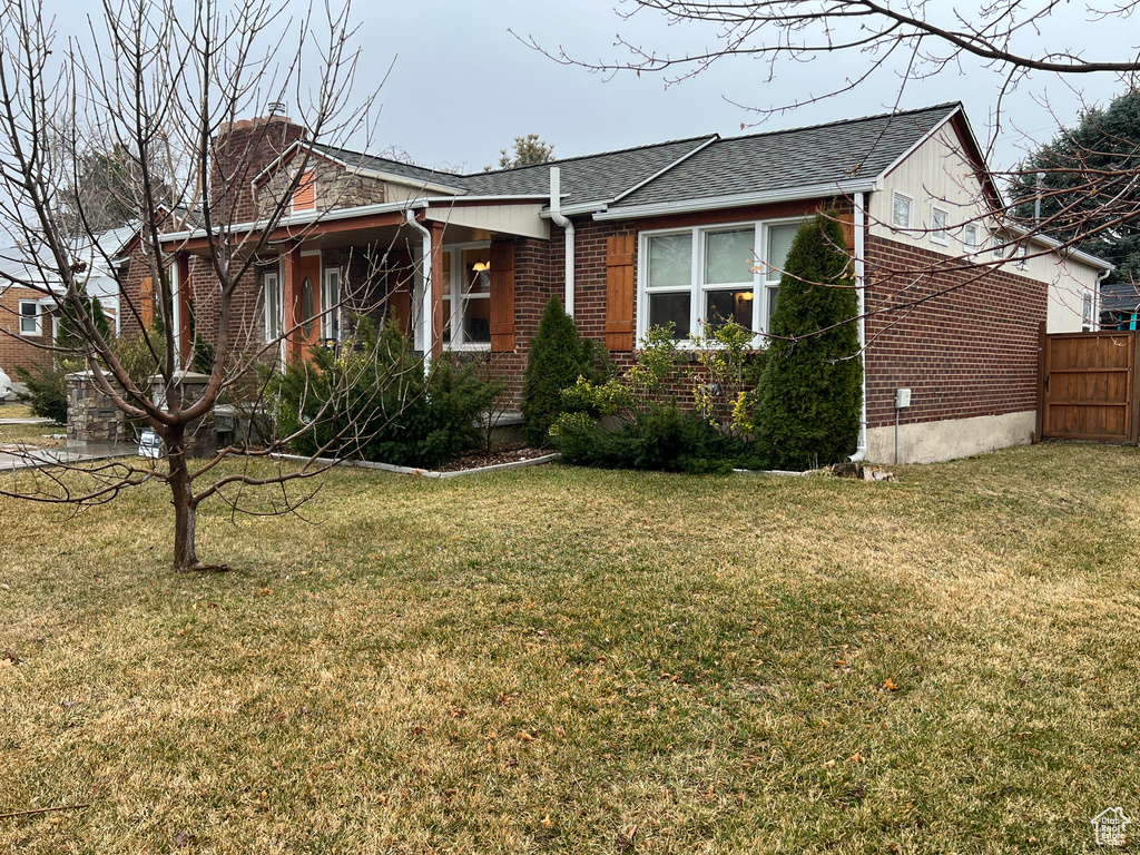 View of front of home featuring brick siding, a front lawn, and fence