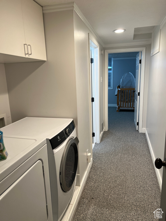 Clothes washing area with washing machine and dryer, cabinet space, carpet floors, crown molding, and baseboards