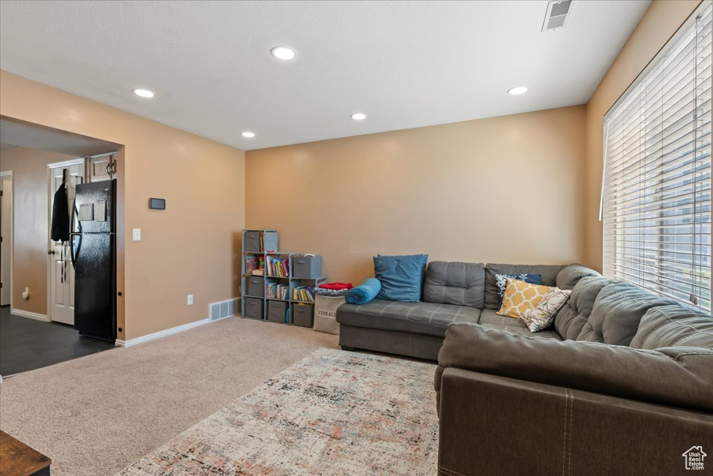 Living area with dark colored carpet, visible vents, baseboards, and recessed lighting