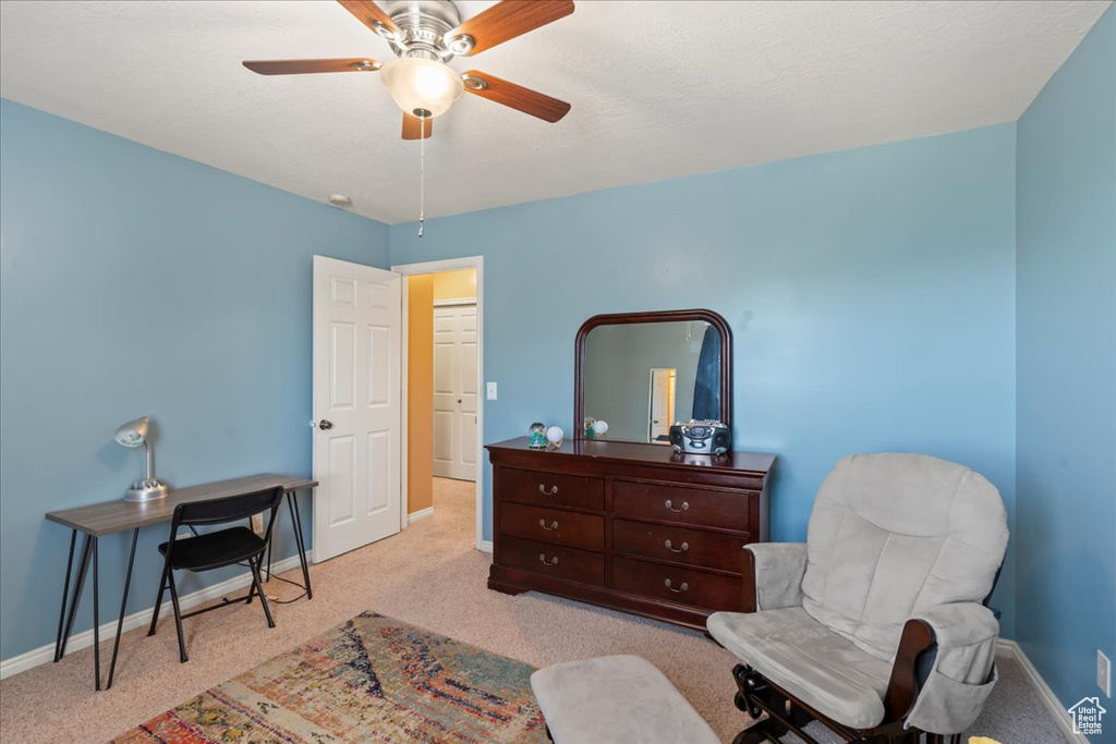 Living area with carpet, baseboards, and a ceiling fan