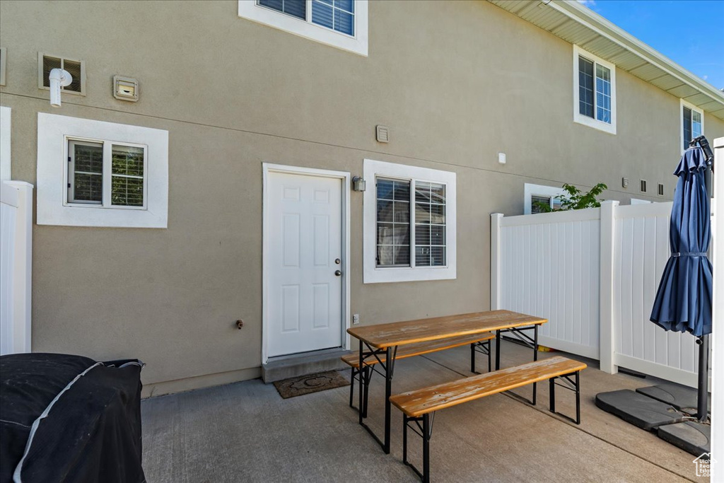 Doorway to property featuring stucco siding, fence, outdoor dining area, and a patio