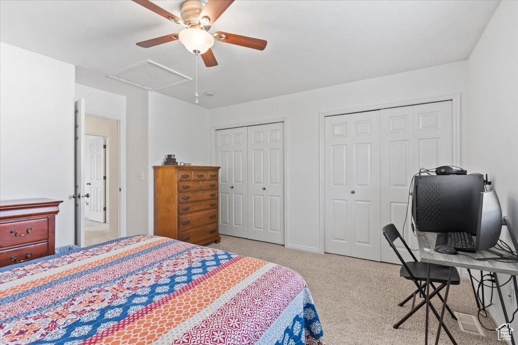 Bedroom with multiple closets, carpet, and a ceiling fan