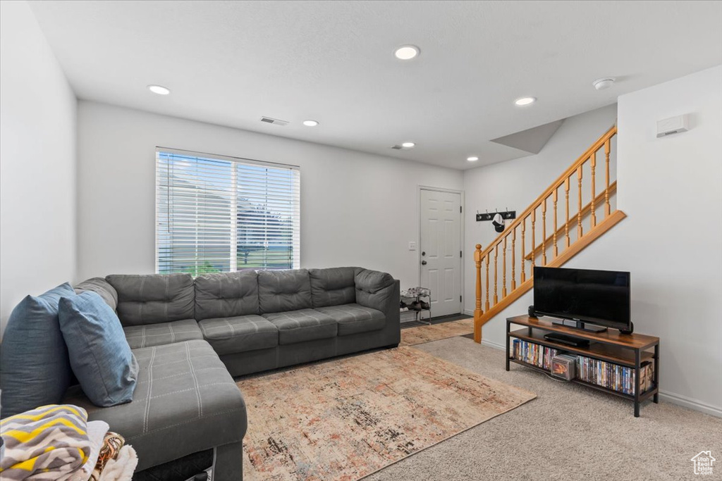 Living area with carpet flooring, stairs, and recessed lighting