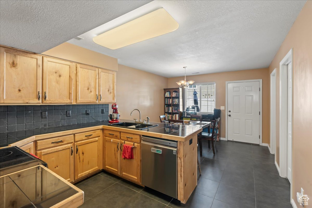 Kitchen featuring backsplash, stainless steel dishwasher, light brown cabinets, a sink, and a peninsula