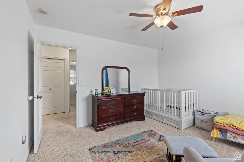 Carpeted bedroom with a nursery area and ceiling fan