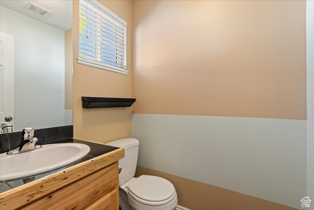 Bathroom featuring visible vents, vanity, and toilet