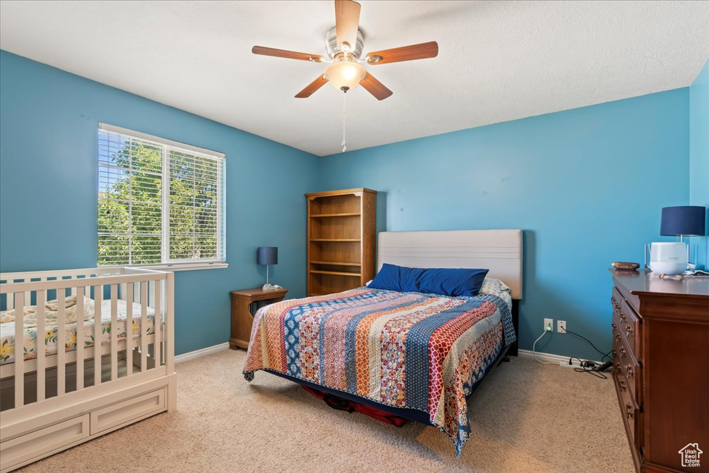 Carpeted bedroom with ceiling fan and baseboards