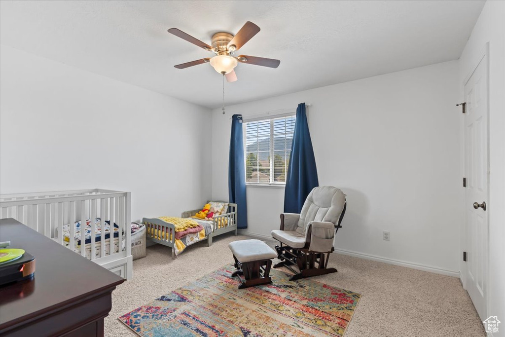 Bedroom featuring carpet flooring, a nursery area, and ceiling fan