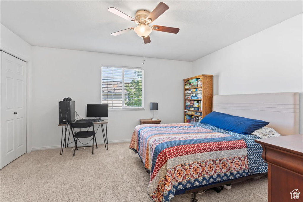 Carpeted bedroom featuring an office area and ceiling fan