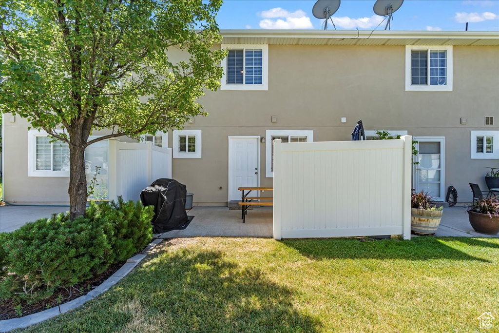 Back of property with a yard, a patio area, fence, and stucco siding