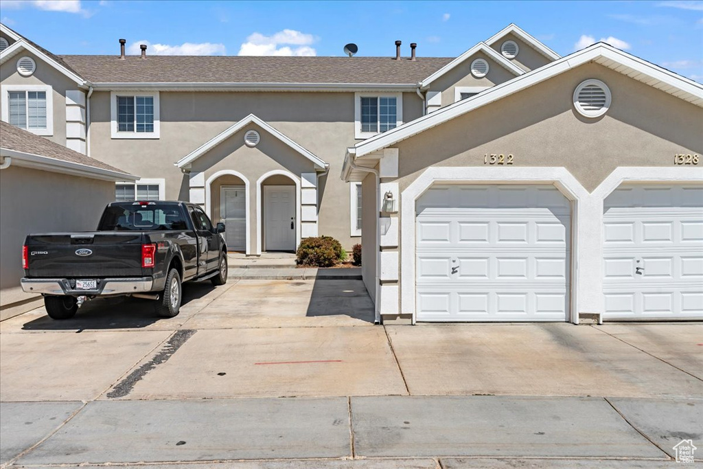 View of property with driveway, a garage, and stucco siding