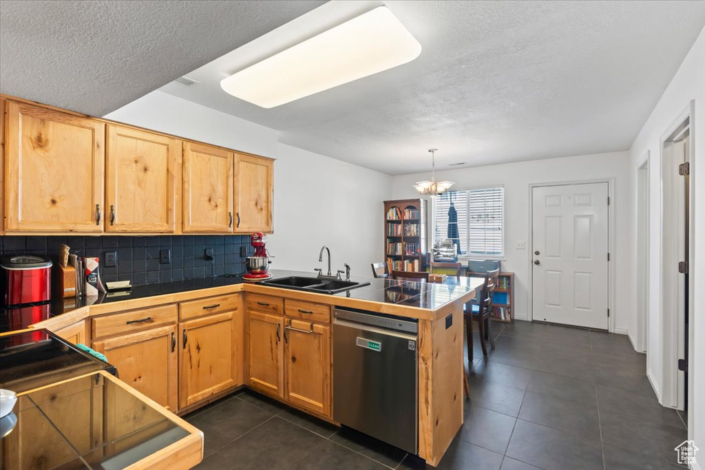 Kitchen featuring stainless steel dishwasher, a peninsula, tasteful backsplash, a textured ceiling, and a chandelier