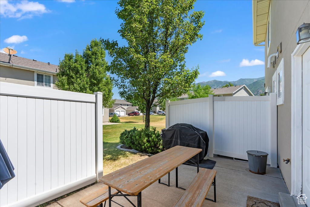 View of patio with fence, a mountain view, and grilling area