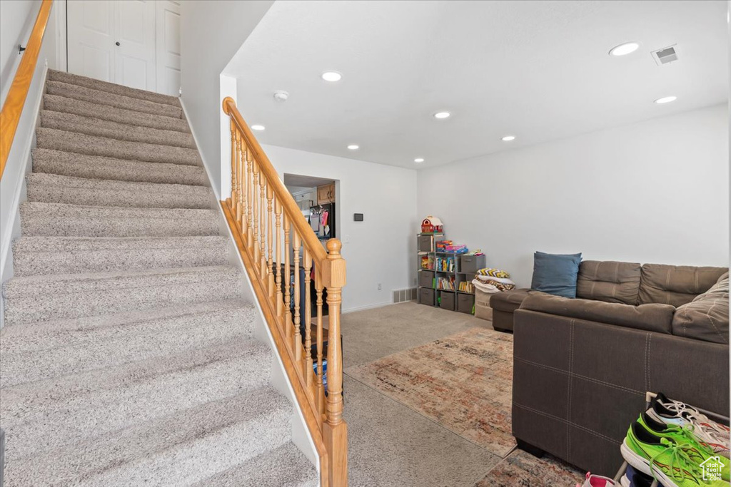 Living area with carpet, recessed lighting, and stairs
