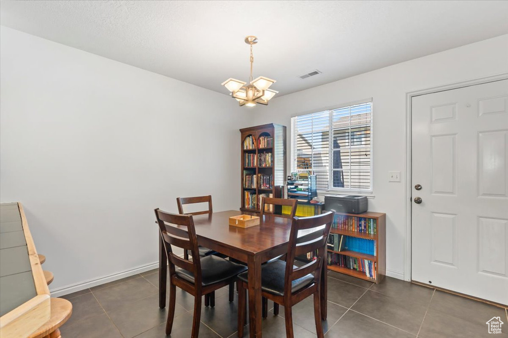 Tiled dining space with a chandelier and baseboards