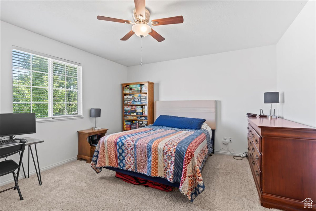 Bedroom featuring light colored carpet, a desk, and ceiling fan