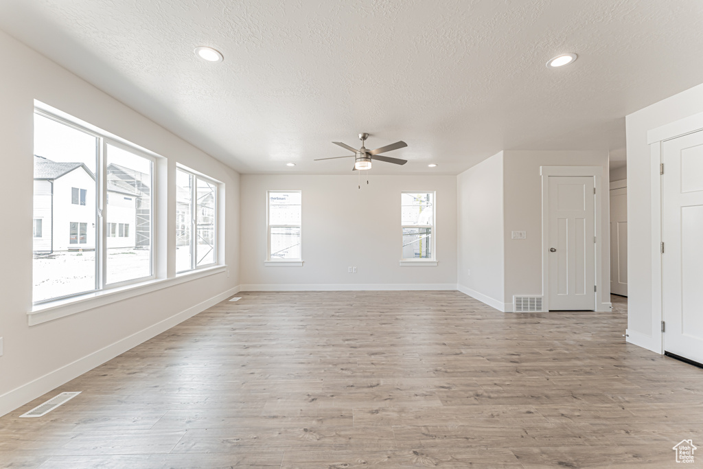 Empty room featuring a textured ceiling, a ceiling fan, light wood-style flooring, and recessed lighting