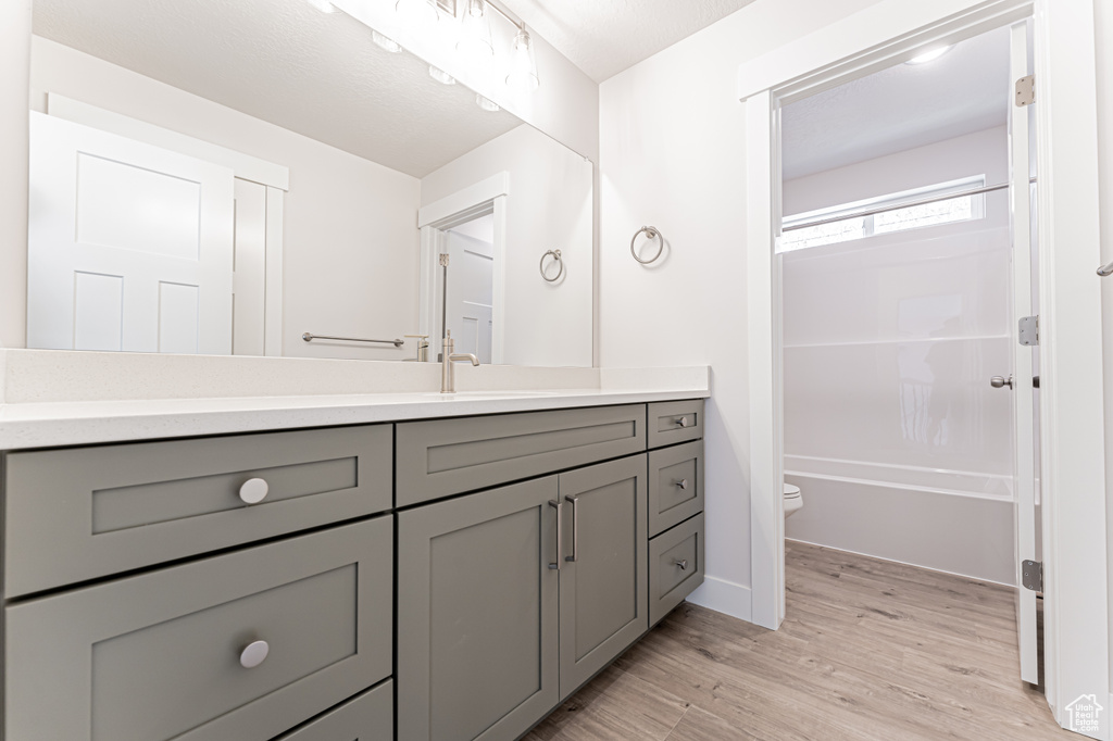 Bathroom with vanity, wood finished floors, and tub / shower combination