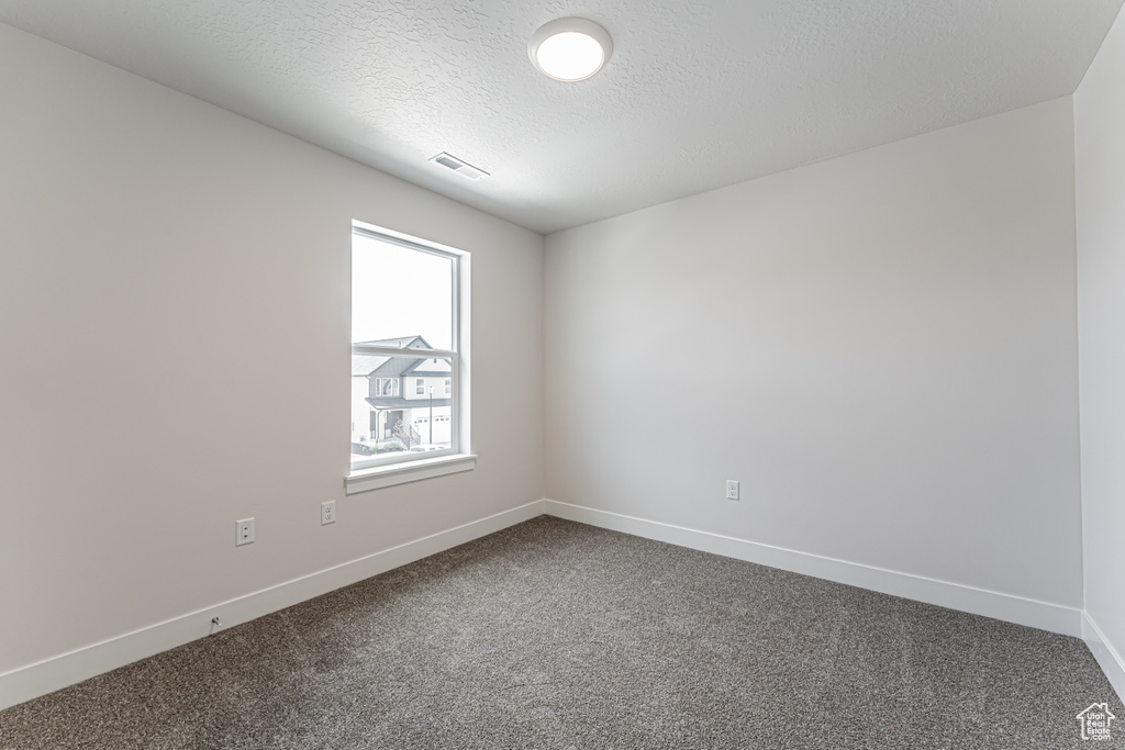 Spare room with dark carpet and a textured ceiling