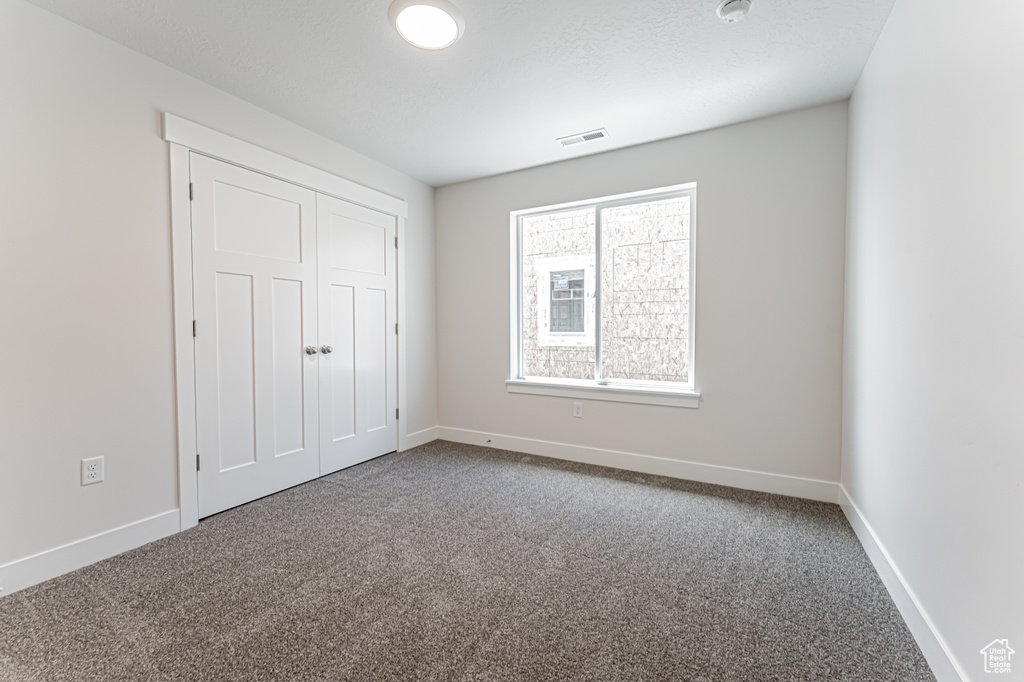 Unfurnished bedroom with carpet and a closet